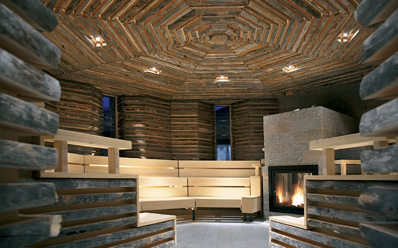 Moderní sauna Klafs umístěná v místnosti obložené neopracovaným dřevem