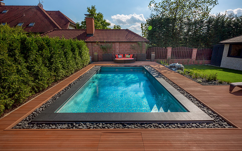 Luxusní nerezový rodinný bazén Imaginox na zahradě s přelivem zakrytým oblázky